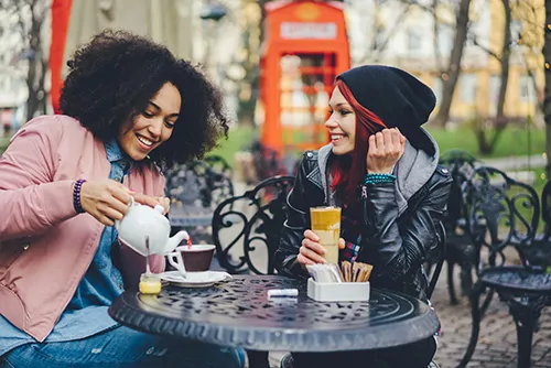 Image of 2 international doctors outside pouring tea and wearing a pink jacket