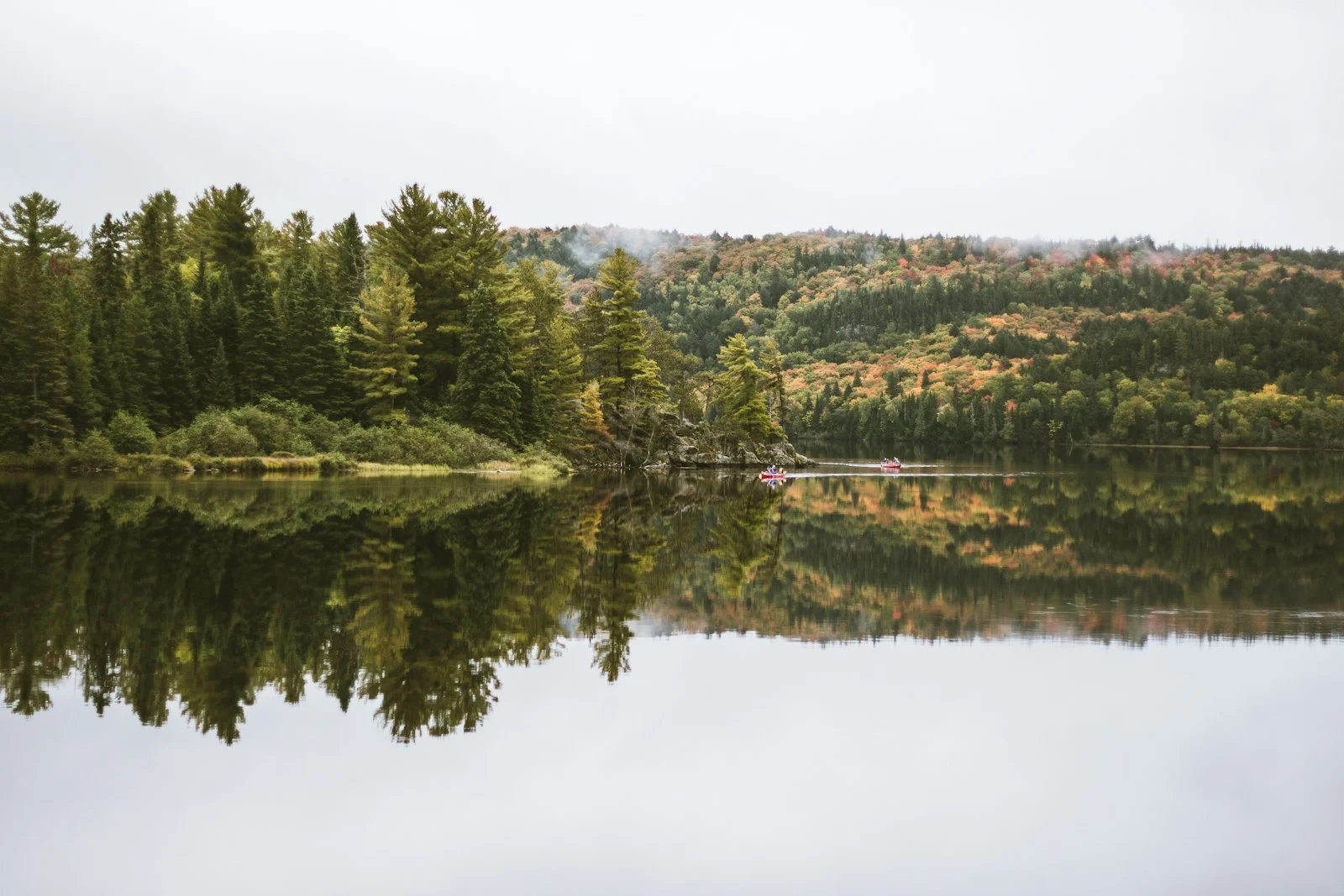 Canoes on a still lake surrounded by autumn forest in Ontario