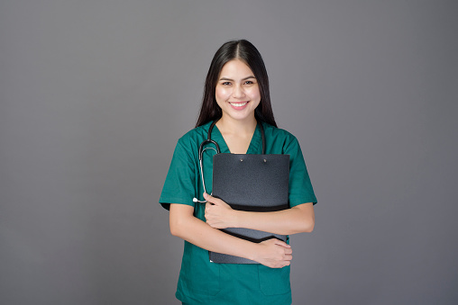 Woman smiling in medical uniform holding a clipboard