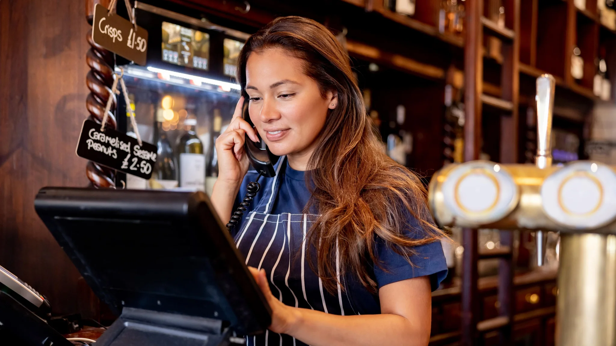 Bartender on the phone using a till