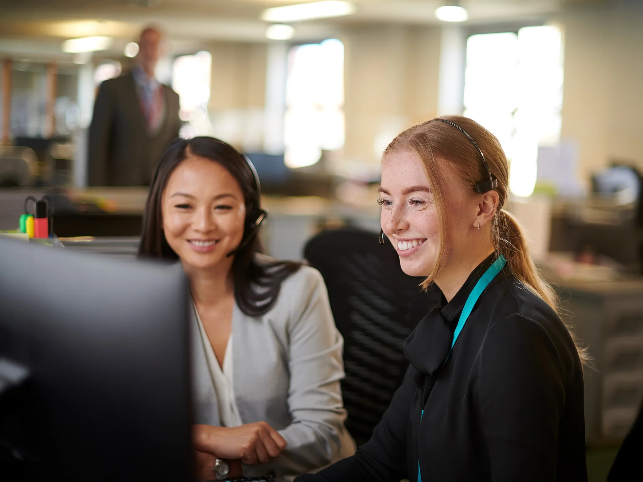 Two smiling office workers looking at a desktop computer