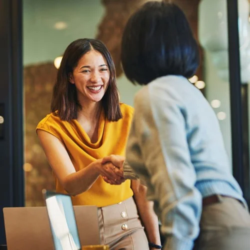 Managed Service image Business person in a yellow top shaking hands with a colleague