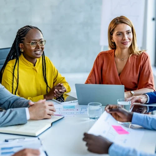 Employer Value Proposition image Two business people sat at a table with a laptop and tablet during a meeting