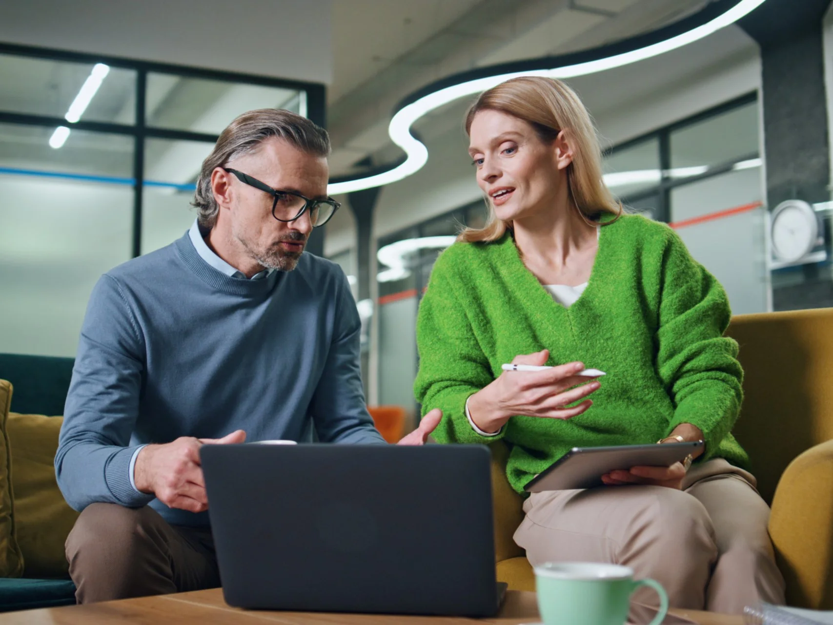 Two professionals in discussion while looking at a laptop