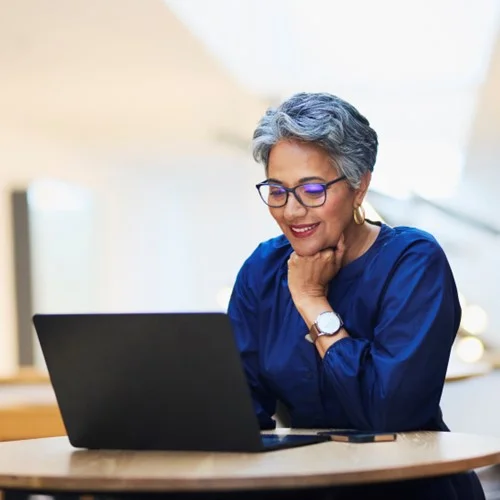 Client Portal image Business person wearing glasses sat looking at laptop