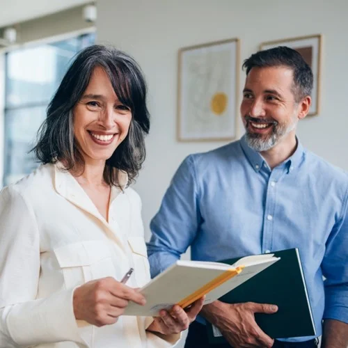 100% Compliance image Two business people reviewing a notebook
