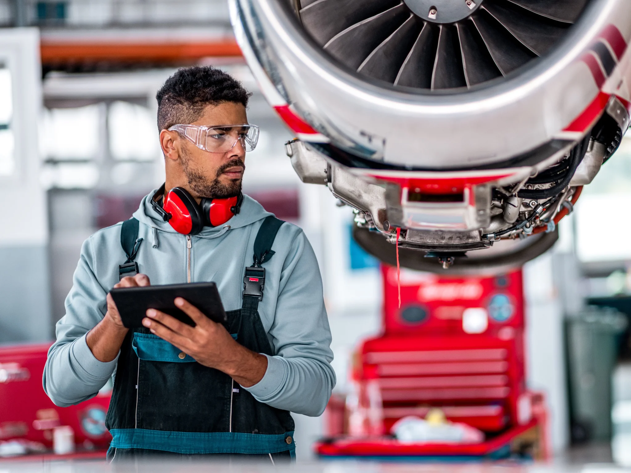 Aerospace Engineer inspecting an engine while holding a tablet