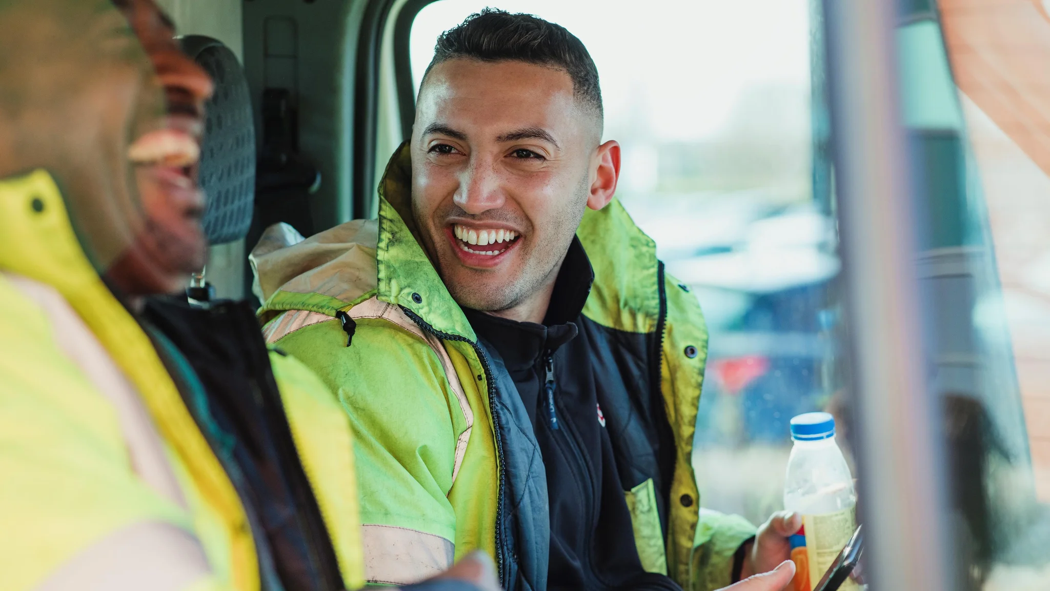 Drivers mate in a vehicle laughing with their colleague
