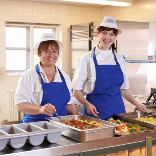 Education image Two Lunchtime Supervisors serving food in a canteen