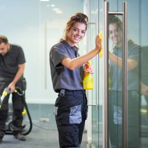 Universities image A Cleaner holding a spray bottle and wiping down glass windows