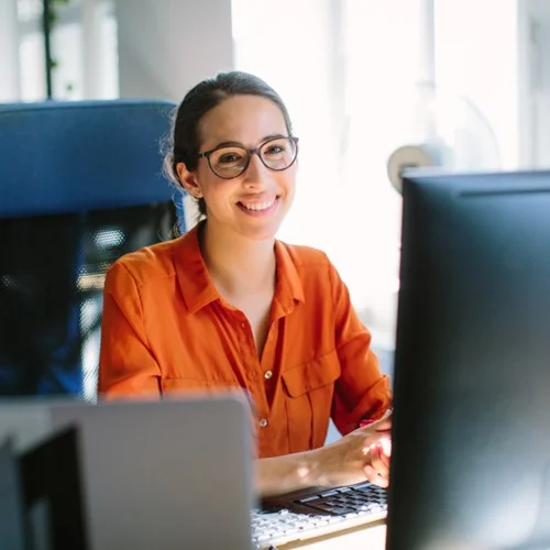 Financial Services image An Accounts Assistant sat at a computer smiling