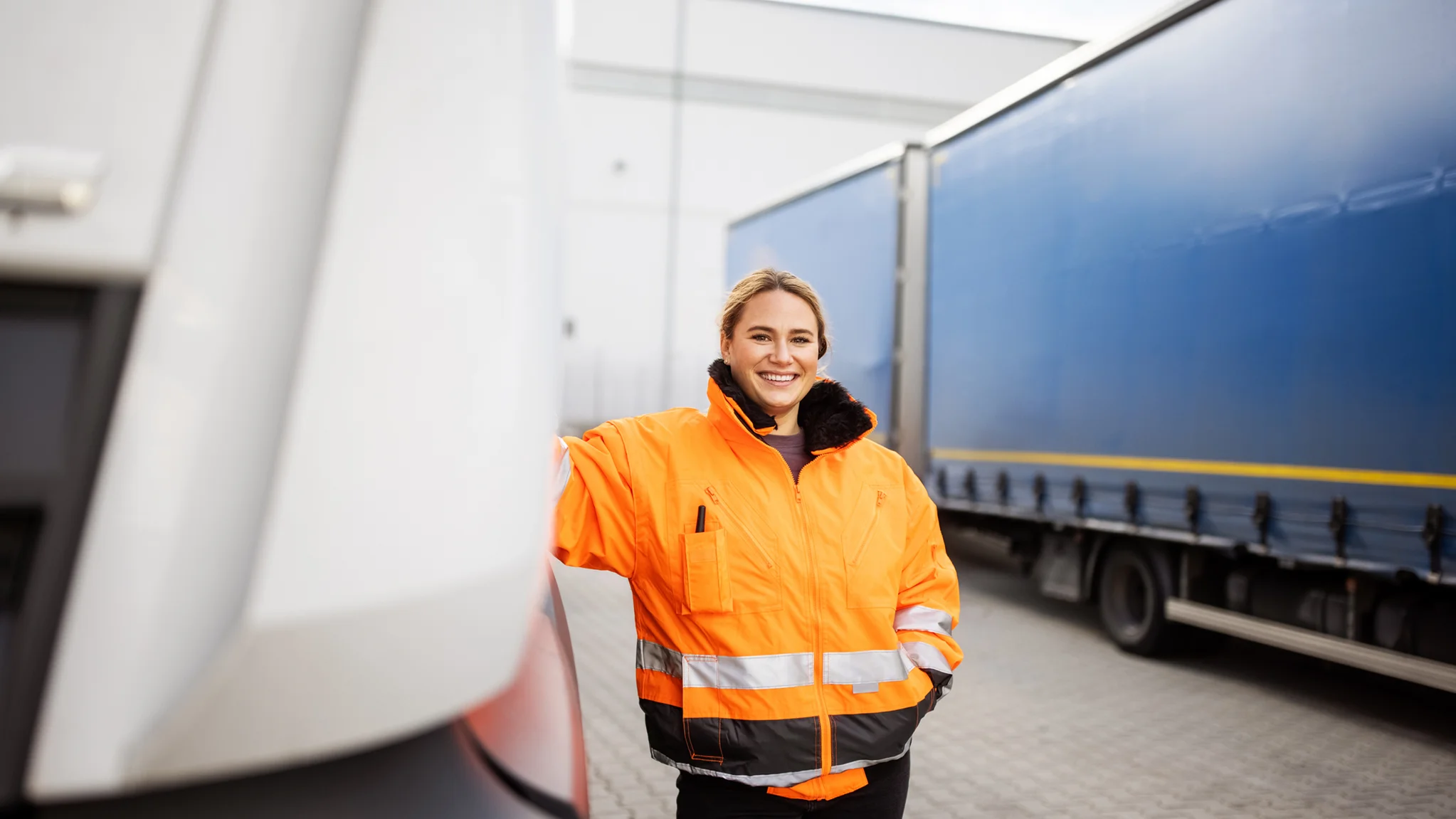 A smiling HGV driver leaning against their vehicle 