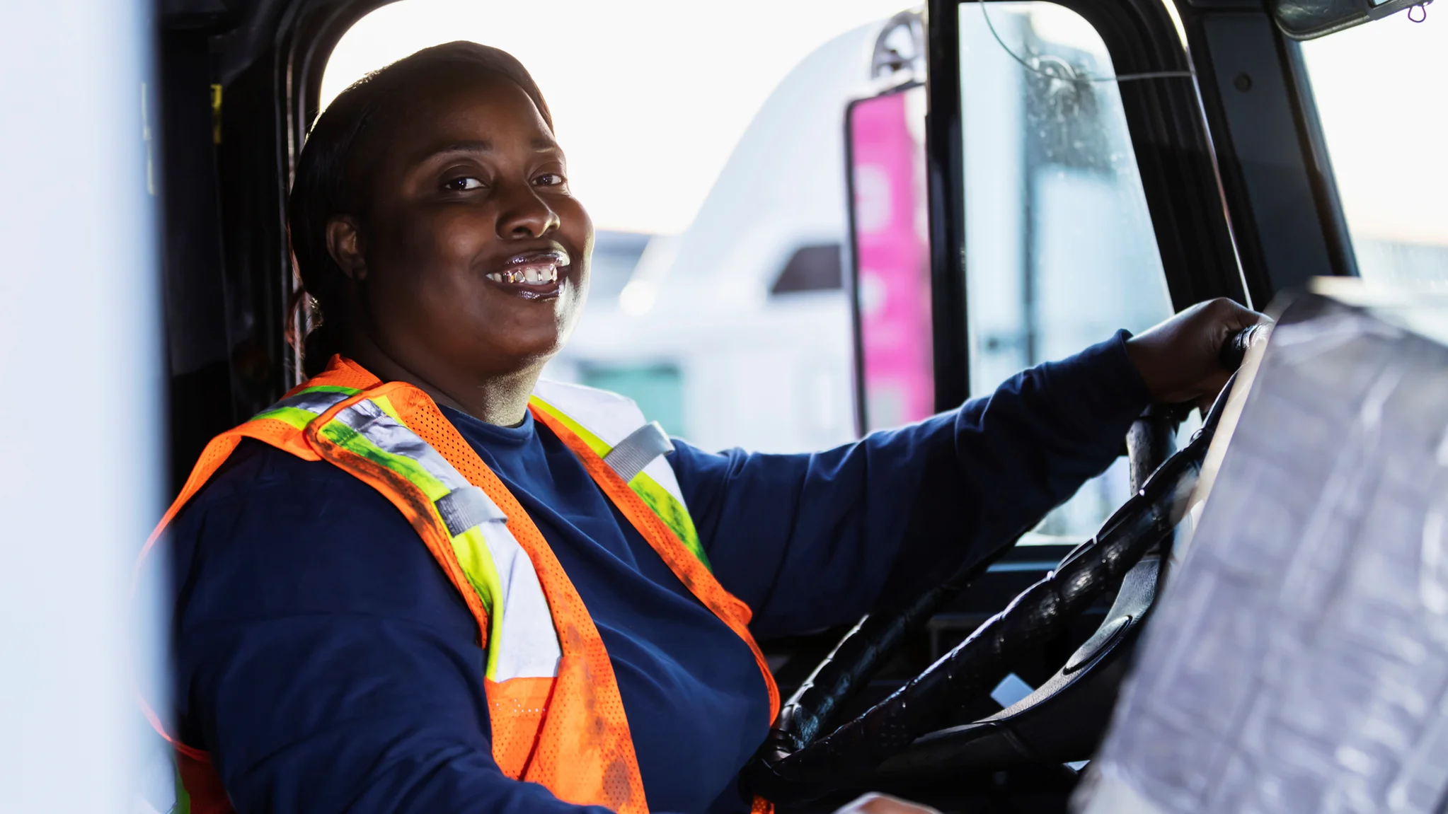 A HGV diver holding their steering wheel and smiling