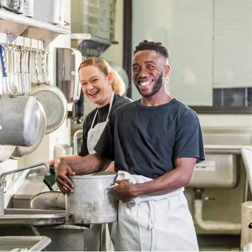 Care Homes image Two Kitchen Porters stood in a kitchen whilst holding a big pot