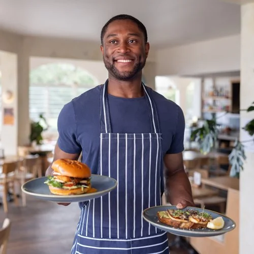 RPO image Waiting Staff wearing an apron and holding two plates of food