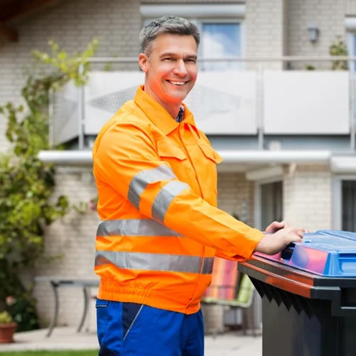 Public Services image A Refuse Collector in an orange hi vis jacket stood with a commercial waste bin