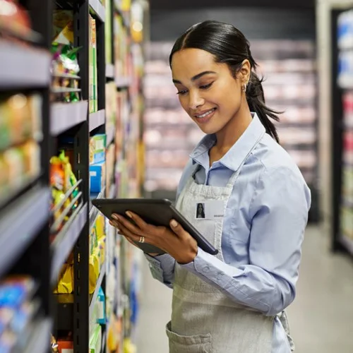 Retail image A Stock Replenisher stood next to shelves looking at a tablet