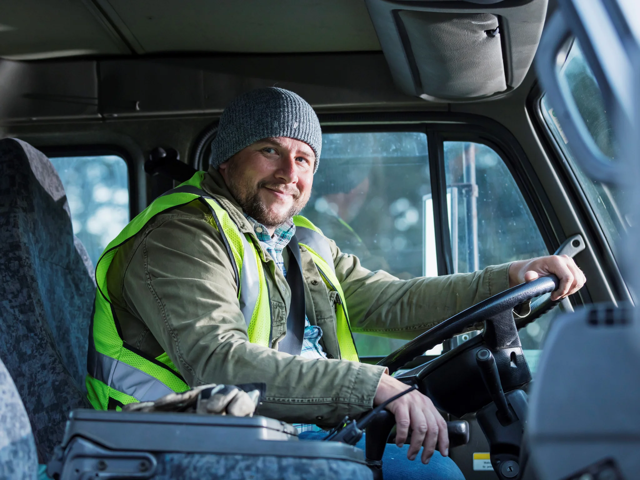 A HGV Driver smiling in the cab of a delivery vehicle