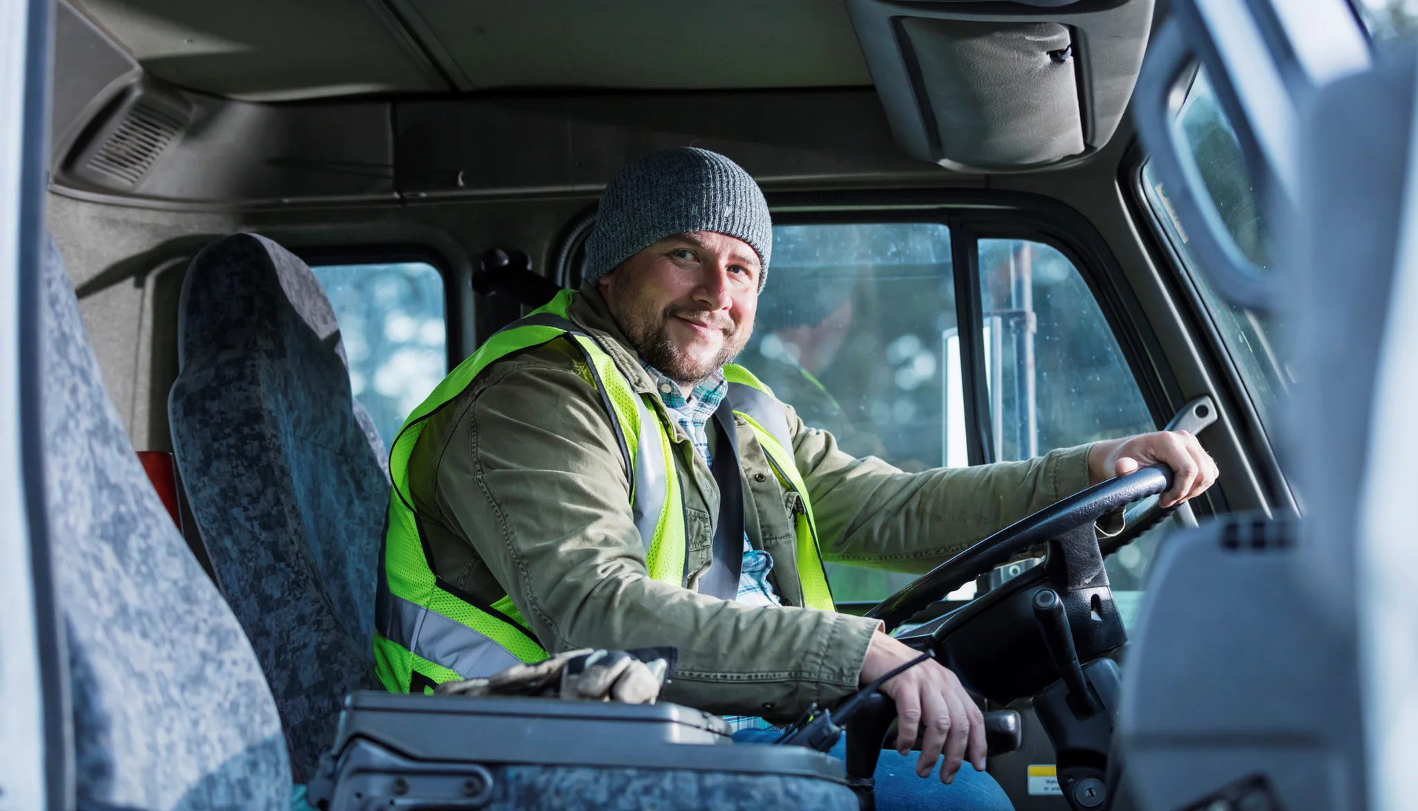 A smiling HGV driver in their vehicle