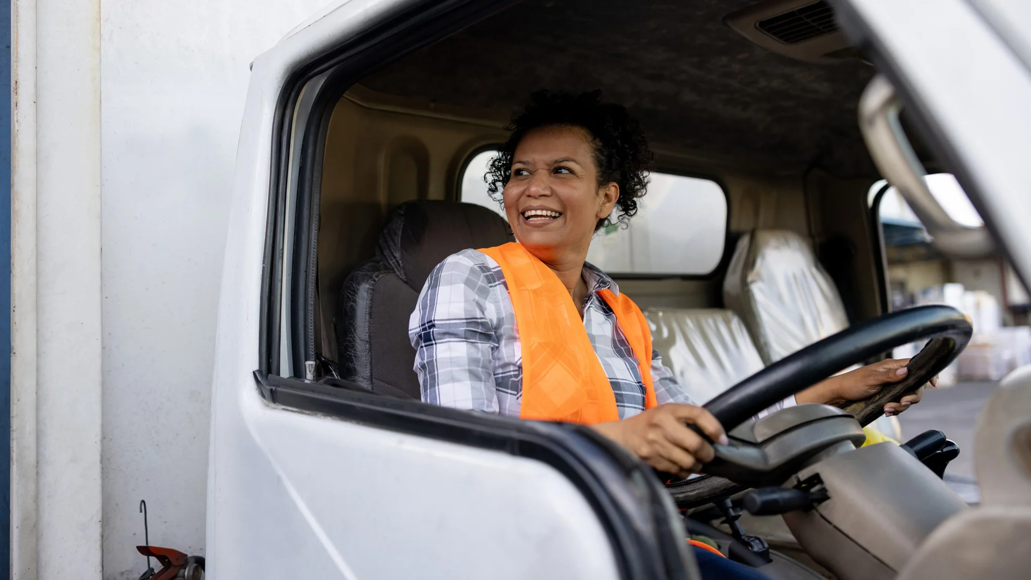 HGV Driver sat behind the wheel whilst wearing an orange hi vis vest