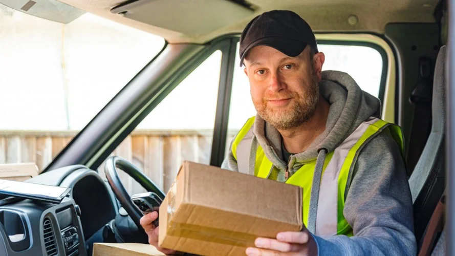 Delivery driver sat in a van holding a parcel