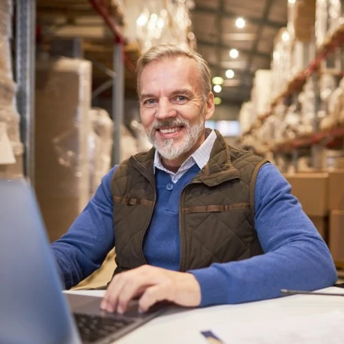 Transport & Logistics image A Supply Chain Manager sat at a laptop in a busy warehouse