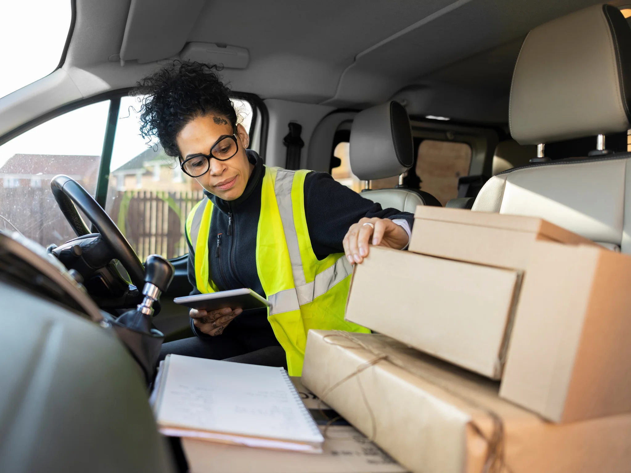 Delivery Driver inside a van holding a tablet and checking parcels