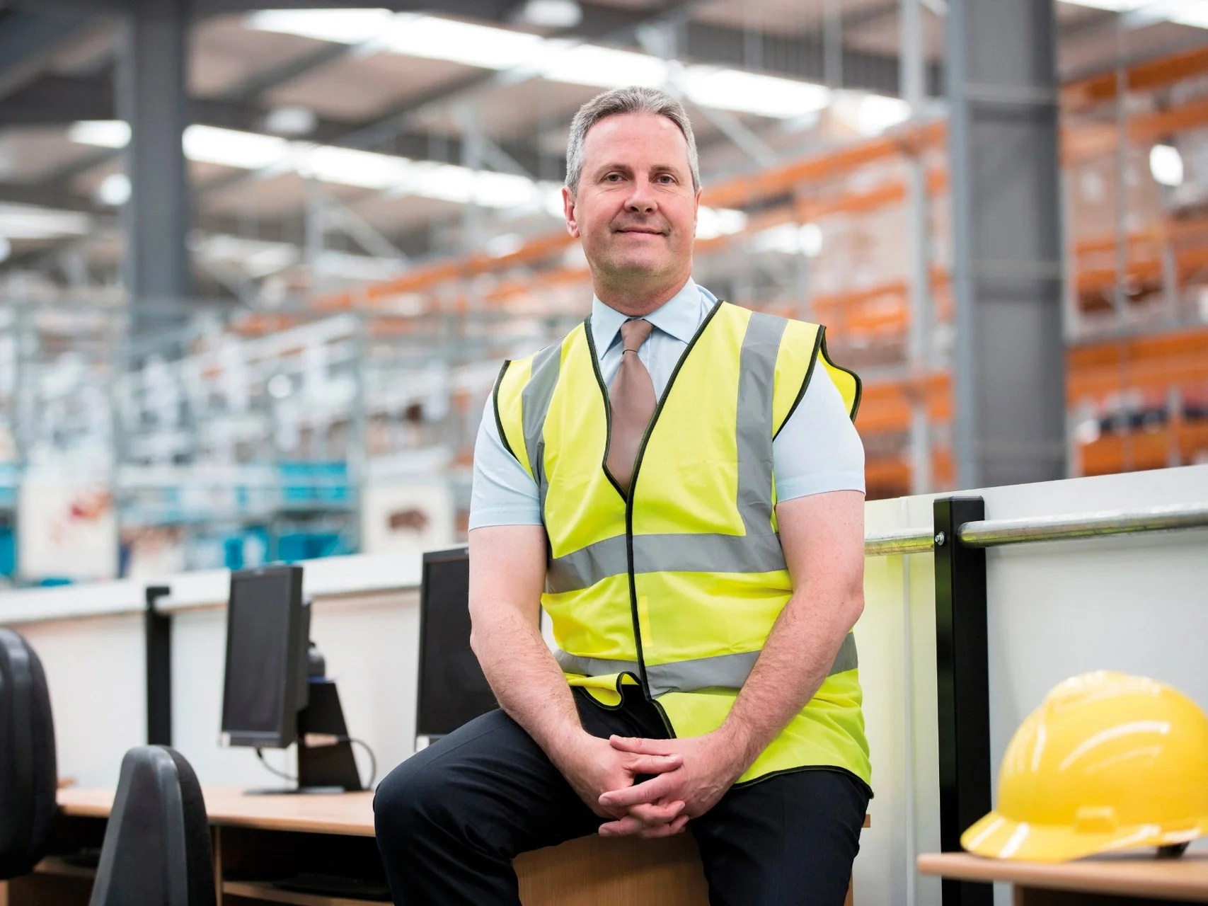 Logistics manager sat on a table in a warehouse