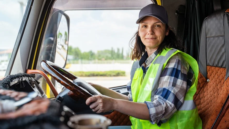 HGV Driver sat behind the steering wheel in a yellow hi-vis jacket