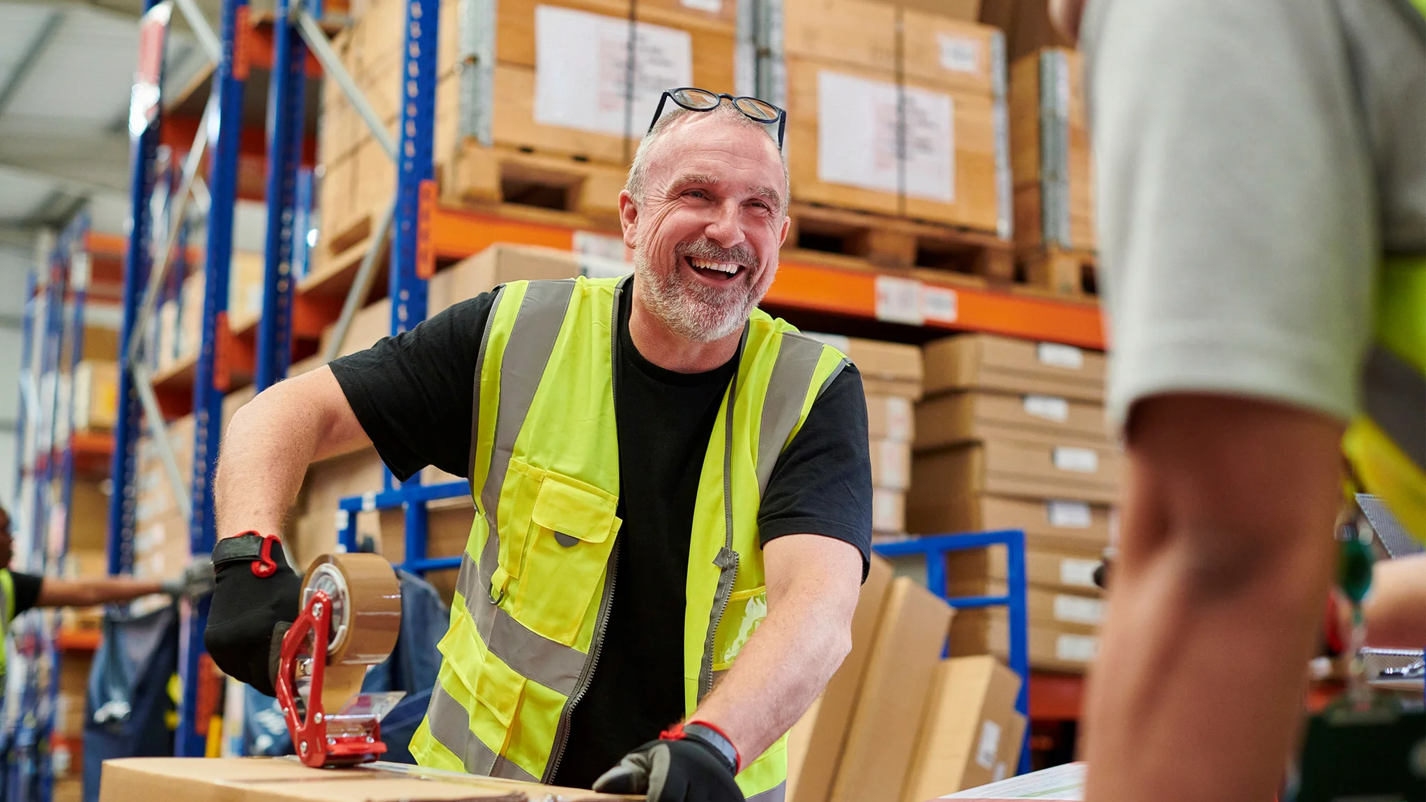 Warehouse worker smiling while handling parcels in a warehouse