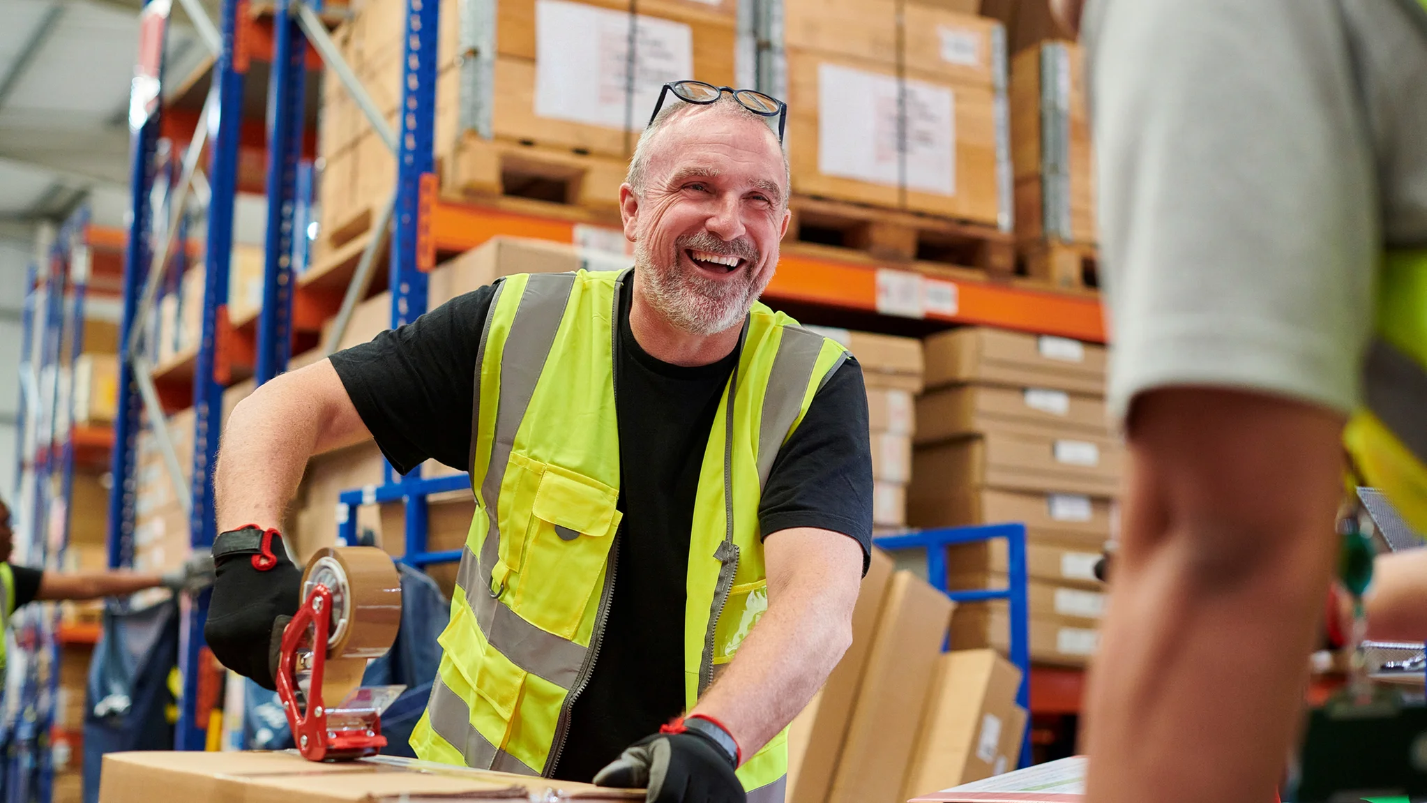Happy warehouse worker sealing parcels in a warehouse
