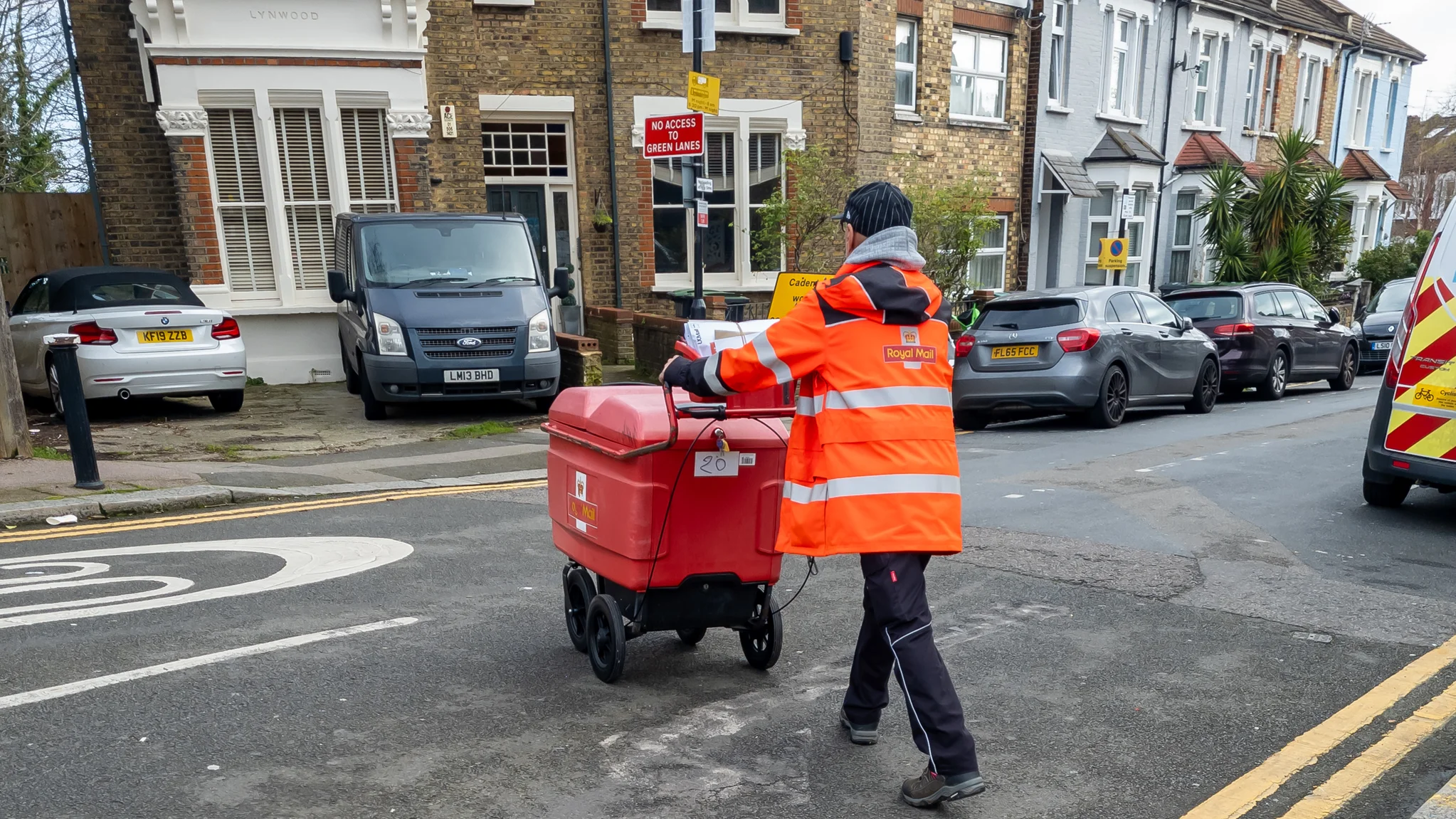 Royal Mail postal worker pushing a delivery cart along a residental street