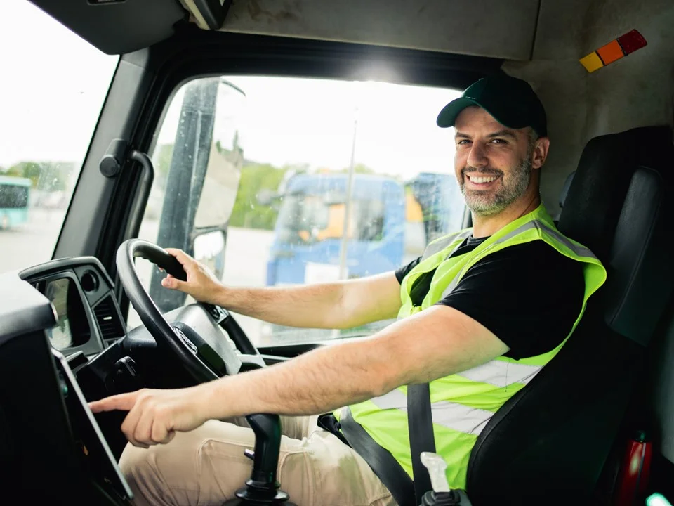 Driver wearing a yellow hi vis vest holding the steering wheel