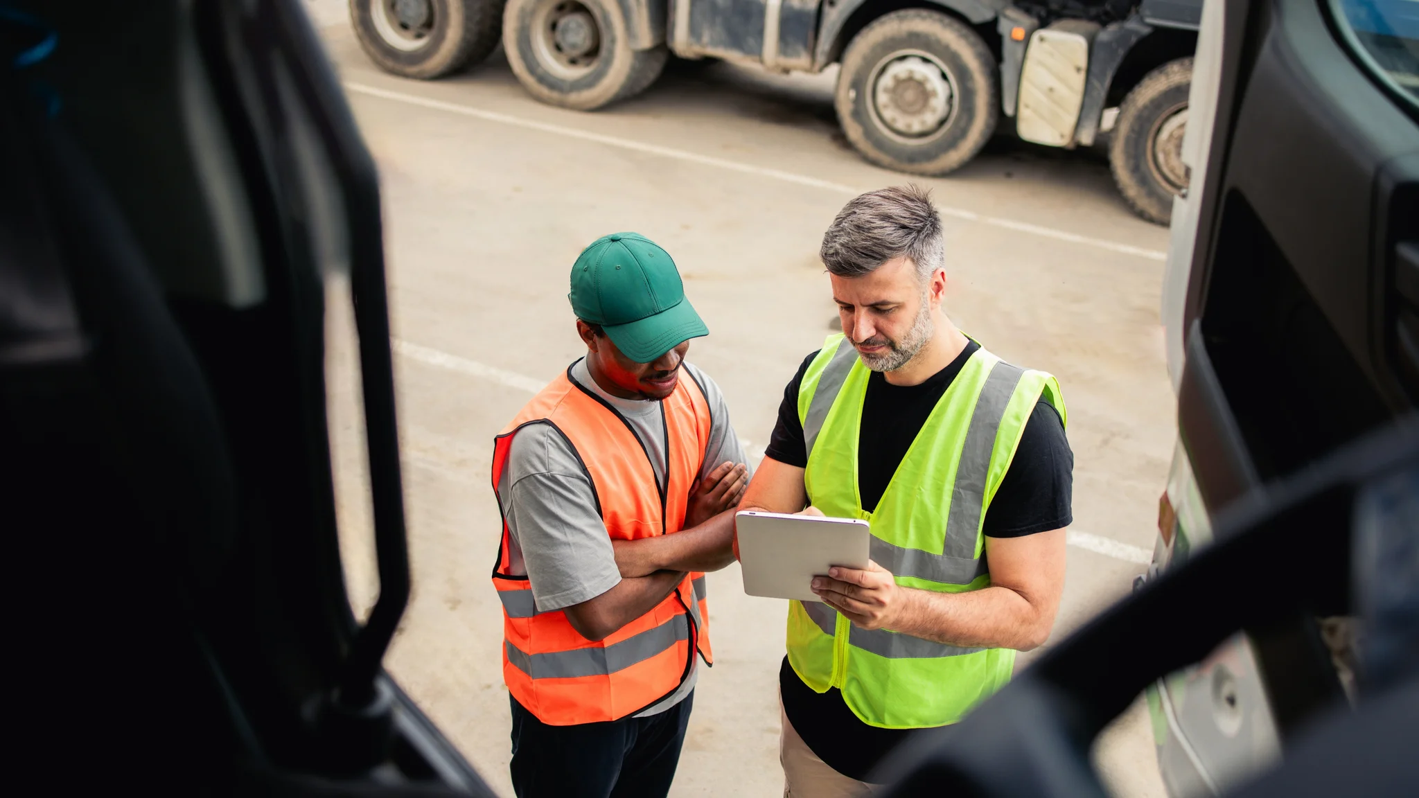 Two delivery drivers at a distribution centre reviewing information on a tablet