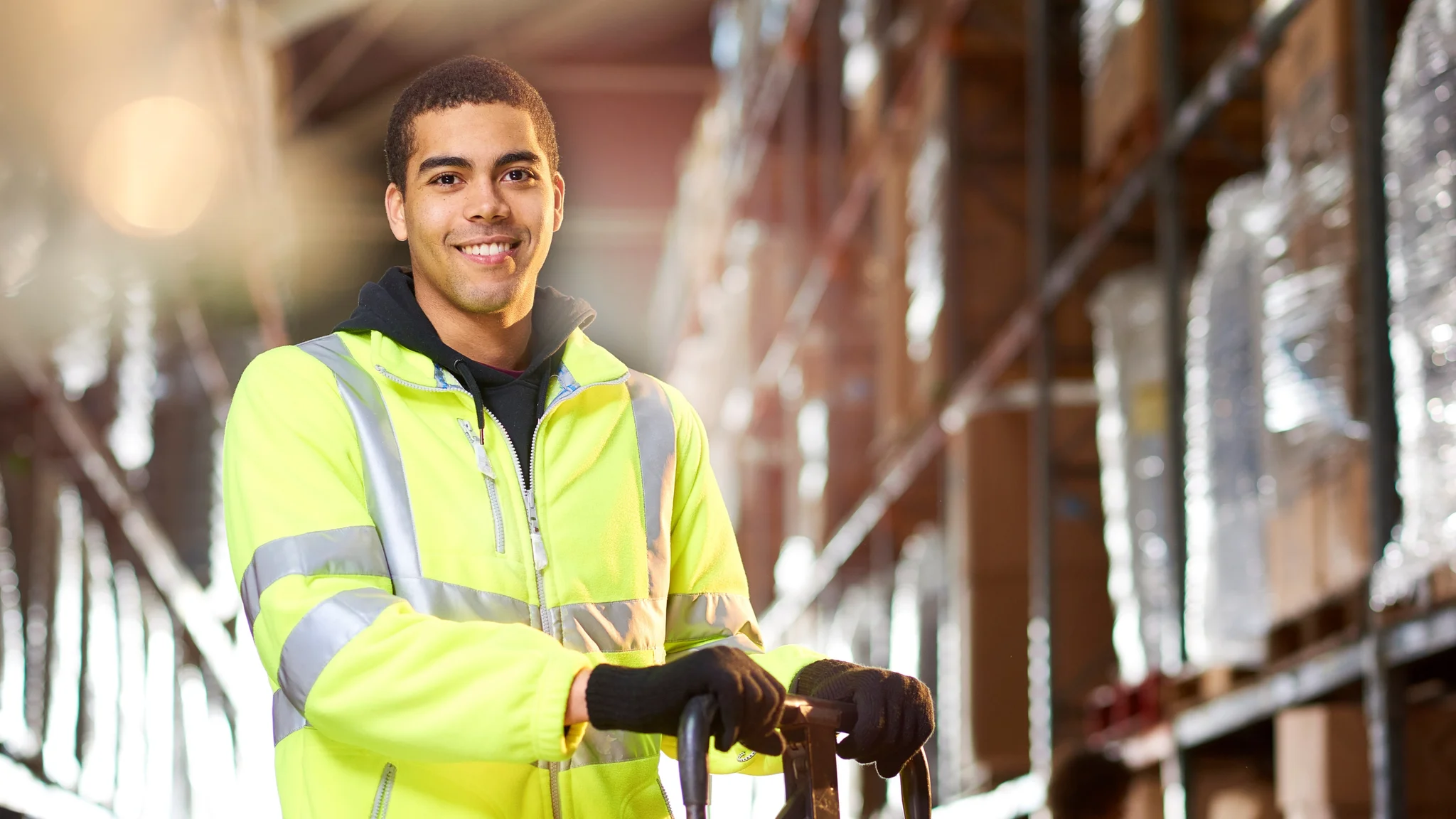 Warehouse worker smiling while operating a pallet truck