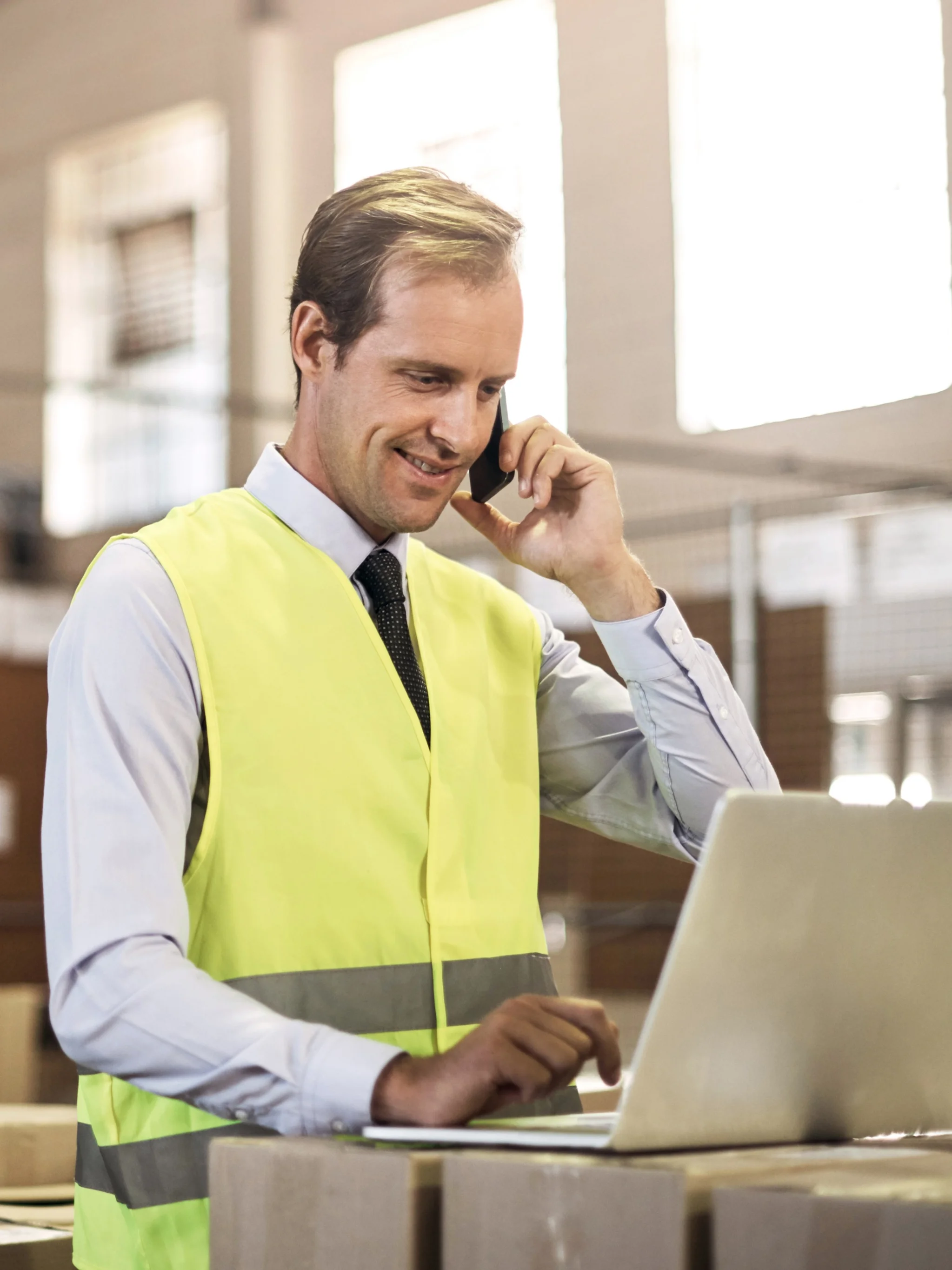 Logistics worker talking on a phone and using a laptop