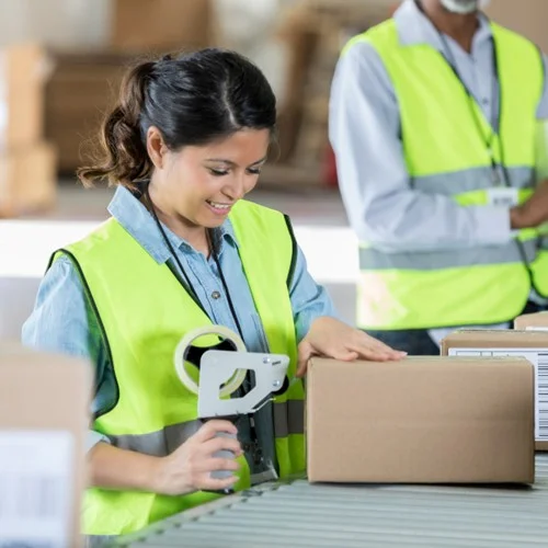 Productivity Solution image A Picker Packer in a yellow hi vis jacket taping up a cardboard box