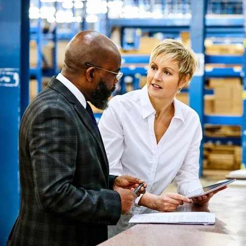 Improved Productivity image Two business people in a warehouse reviewing a tablet