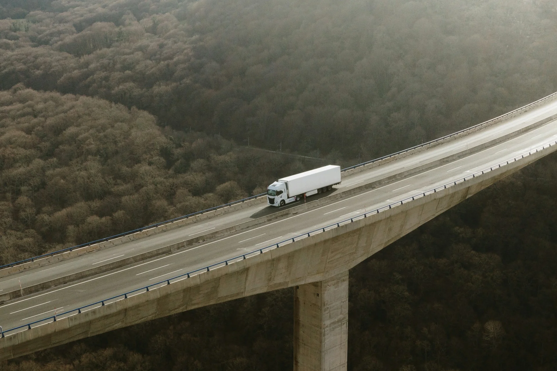 aerial-view-of-a-semi-truck-on-a-tall-highway-viaduct-in-a-mountain-area-