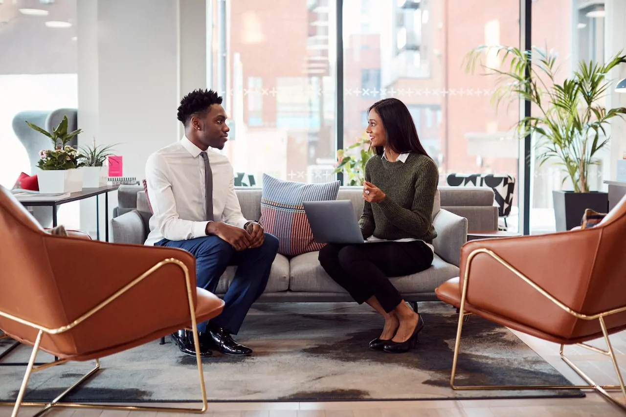 two people sitting on a sofa having a meeting in a stylish office