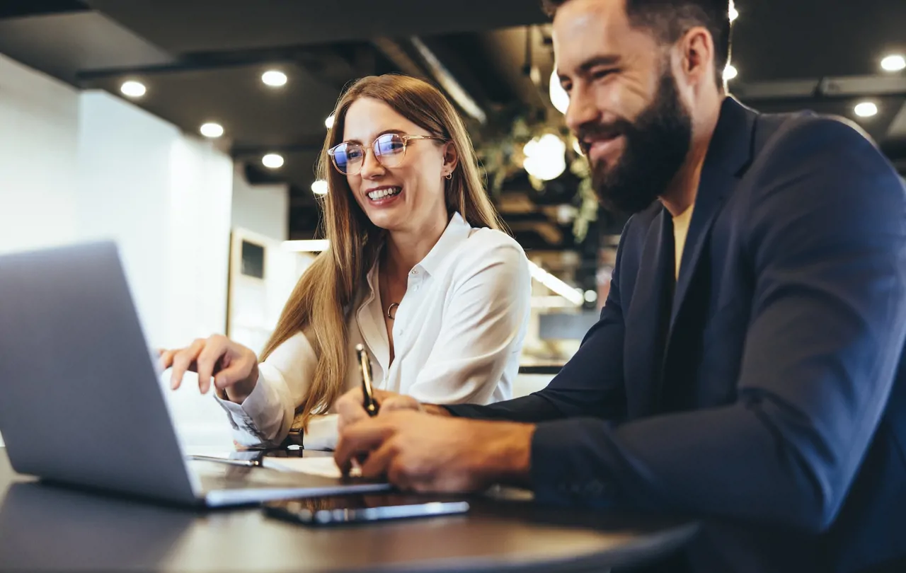 Two colleagues Sat at a desk on a laptop