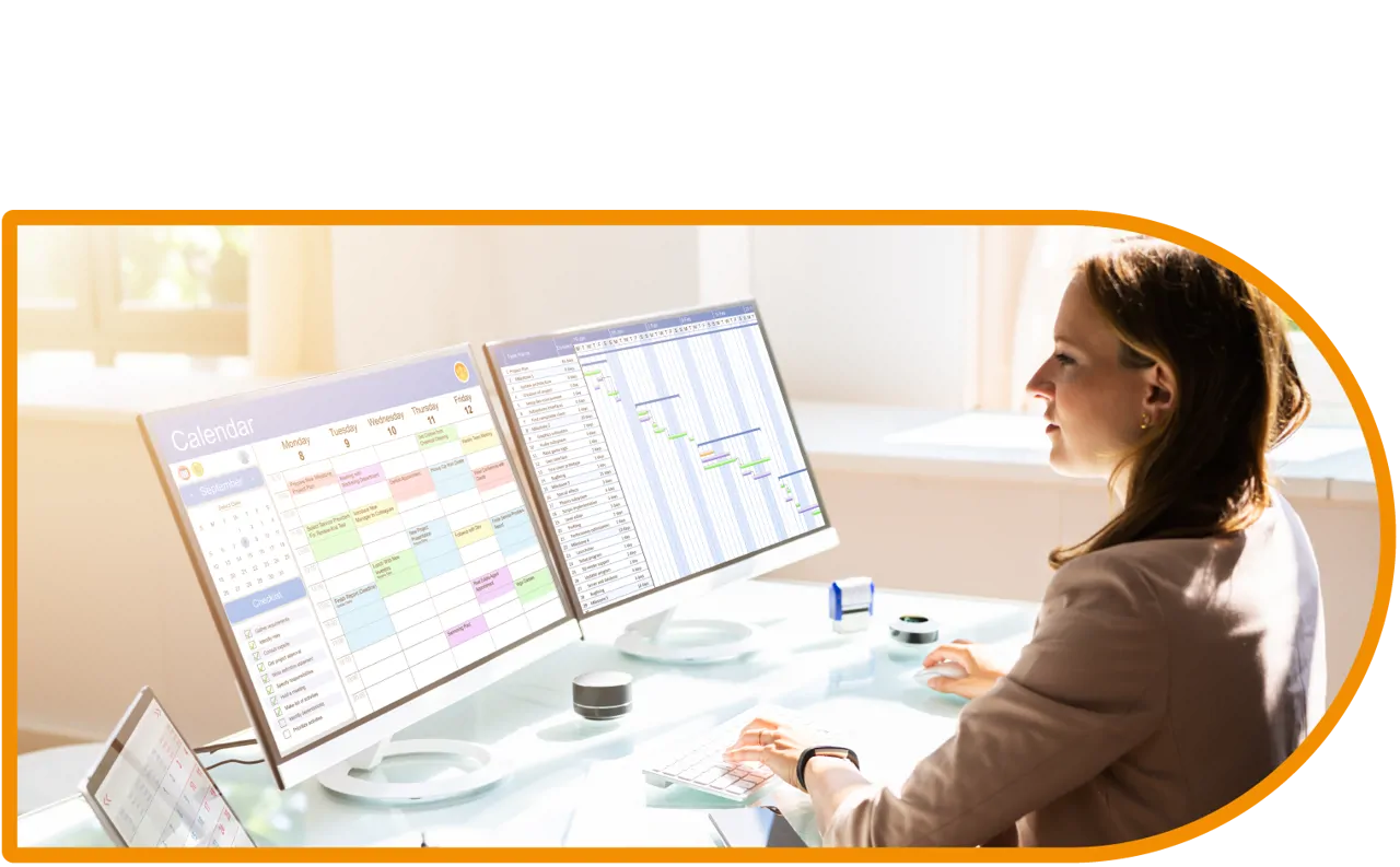 A woman looking at calendars on two computer screens