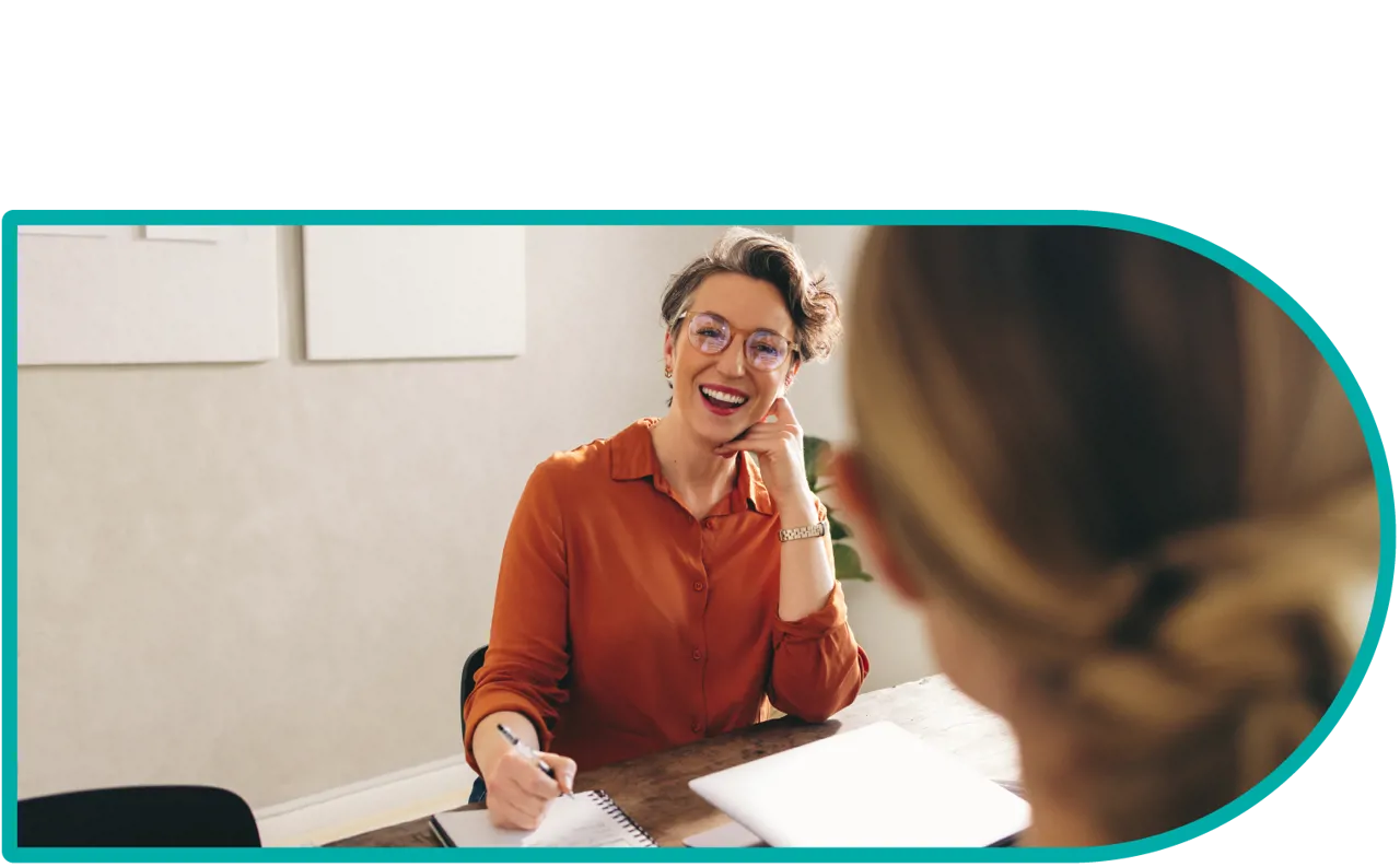 A woman at a conference table laughing with another person in the foreground.