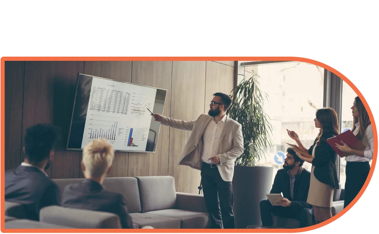 A smartly dressed man presenting a slide to a room of people.