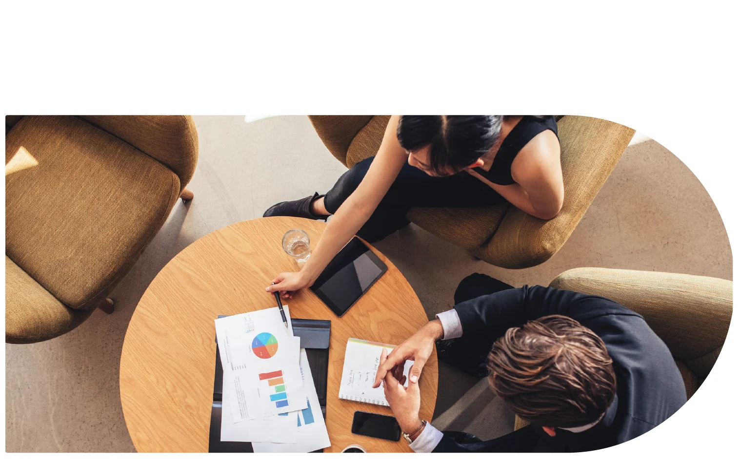 Ariel photo of two people sat at a desk with papers on the desk of charts and graphs