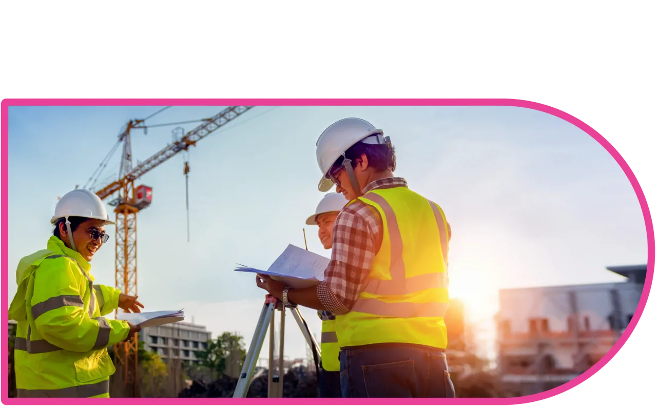 Construction workers on site wearing hard hats and high vis jackets with a crane in the background