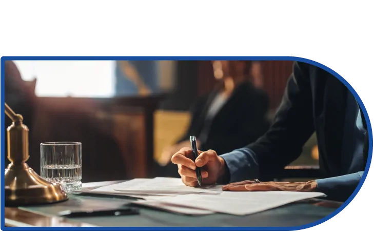 A person sat at a courtroom desk, writing with a pen.