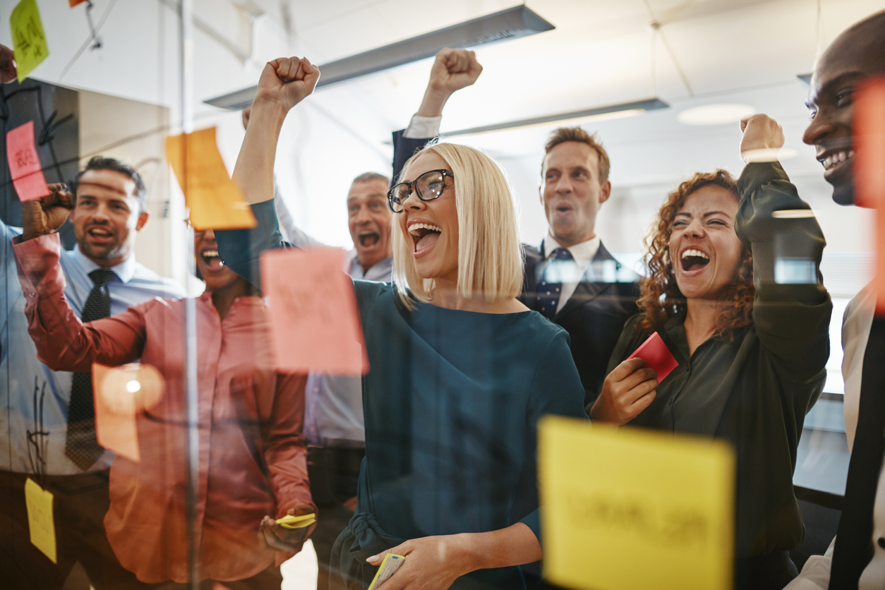 A group of recruitment consultants. They are looking at figures on post-it notes and cheering, as if celebrating positive results.