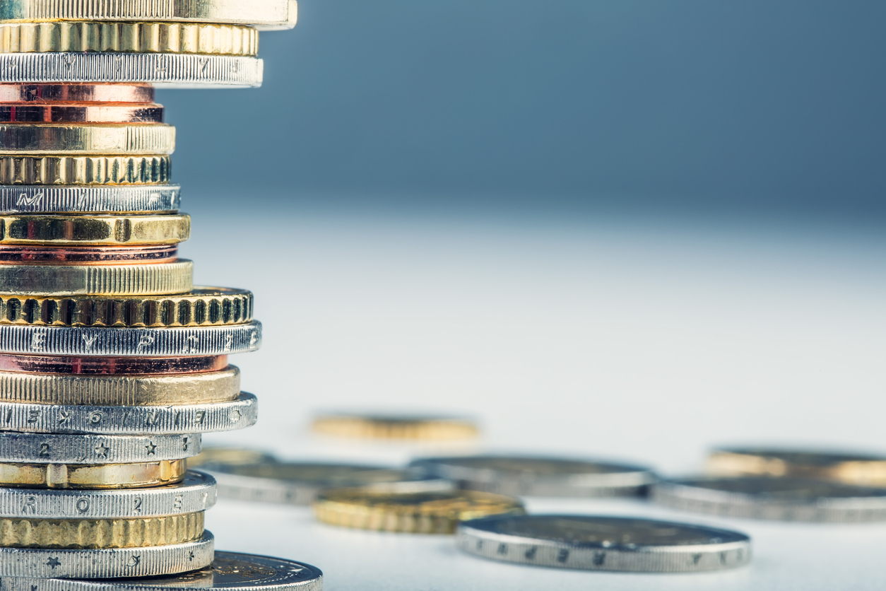 An image of several different coins scattered across a surface and piled on top of each other. The image is supposed to symbolise 'money', a key topic of the article.