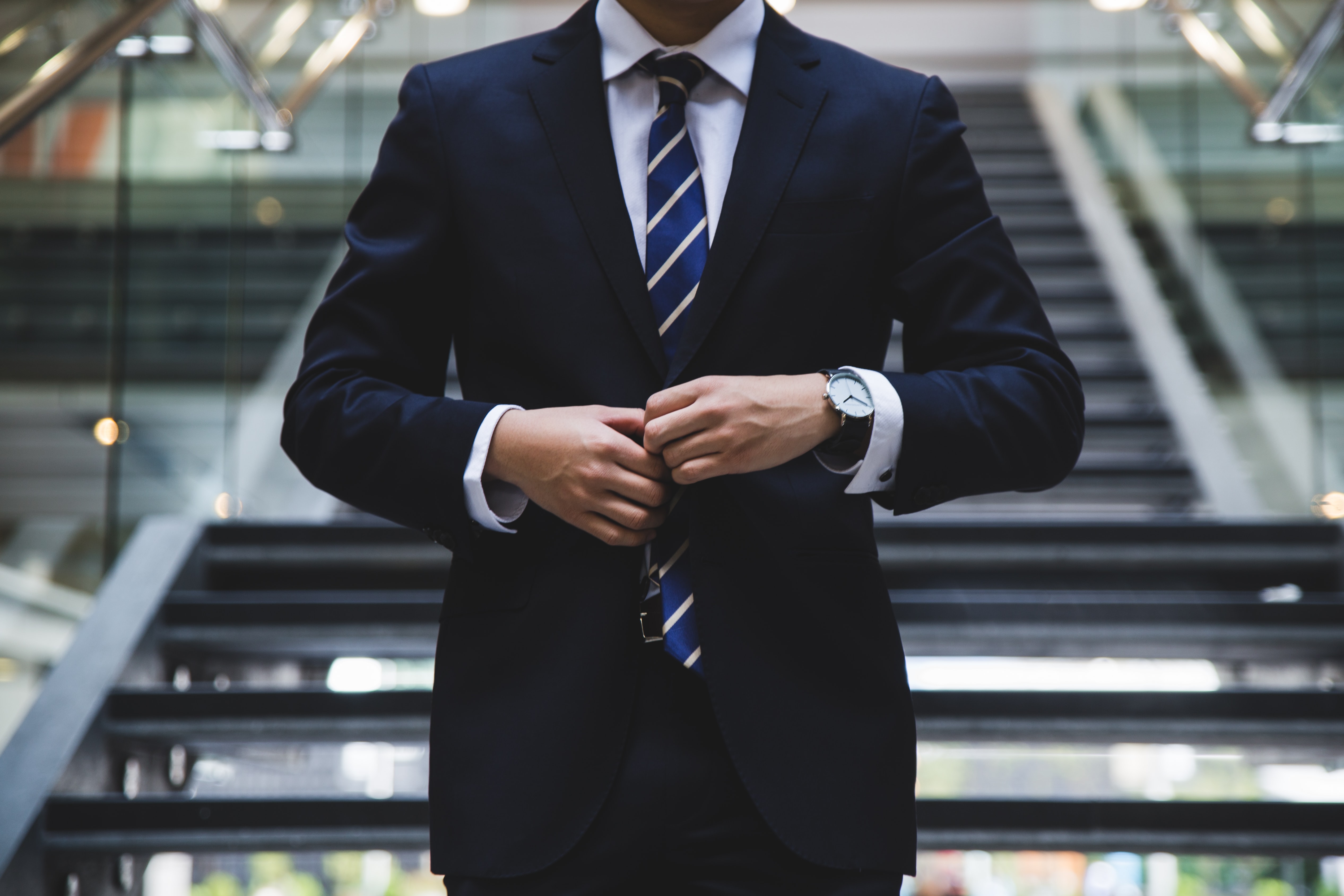 A person dressed in a smart suit, tie and shirt. You can not see their head or the face, the image focuses on their smart clothing.